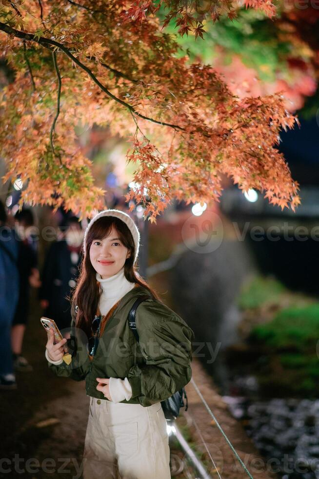 Asian woman in a fashionable jacket enjoys the beauty of urban nightfall in Japan. A festive portrait capturing Christmas cheer and snowy delight. photo