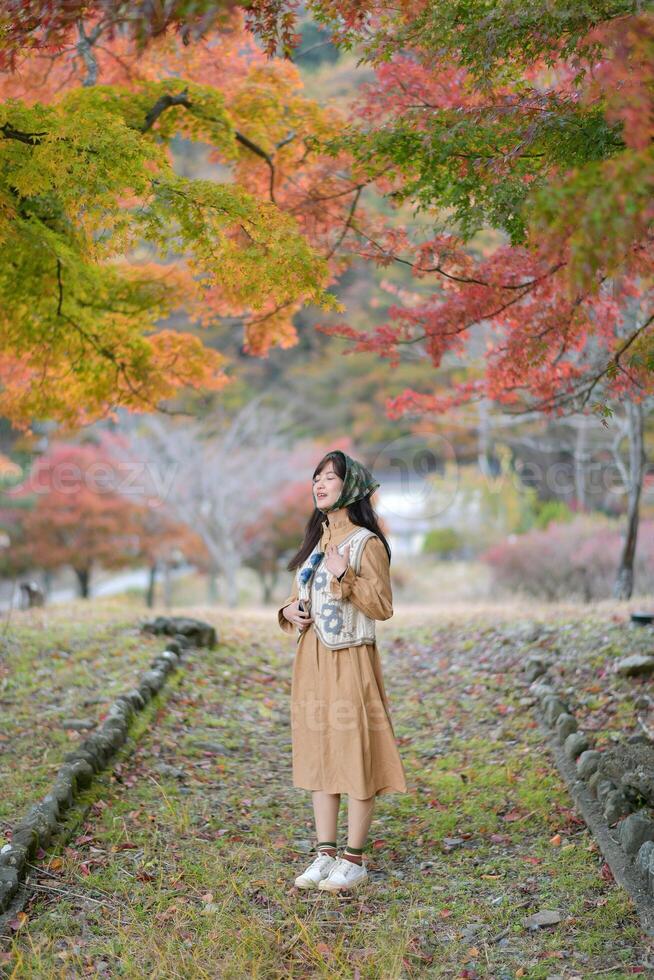 A woman in a coat stands in front of autumn trees photo