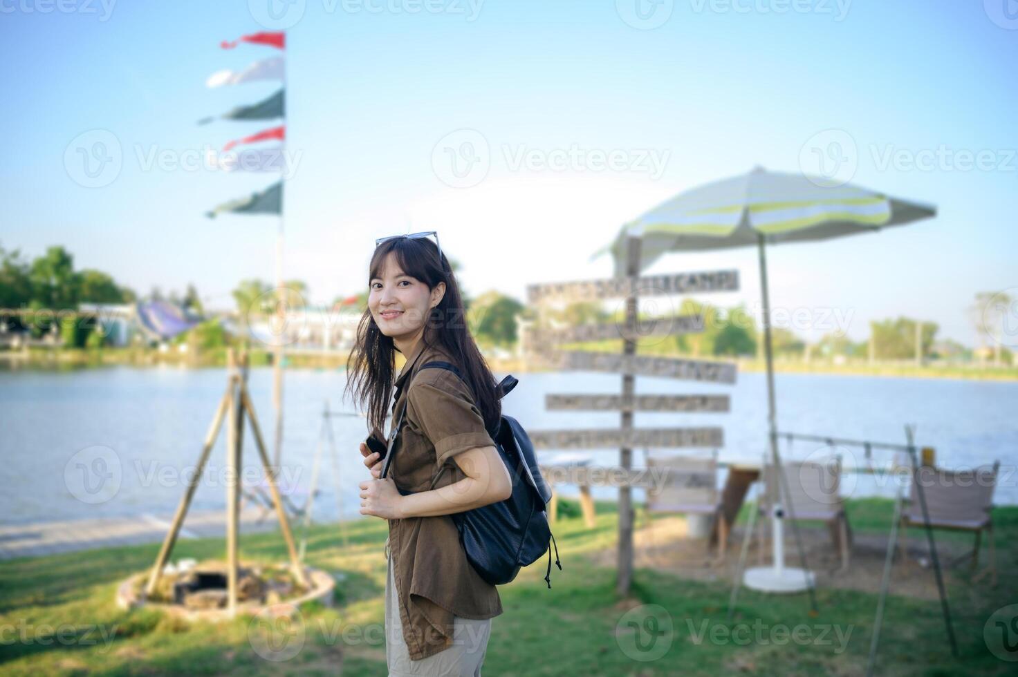 Asian woman with backpack standing in front of a lake photo
