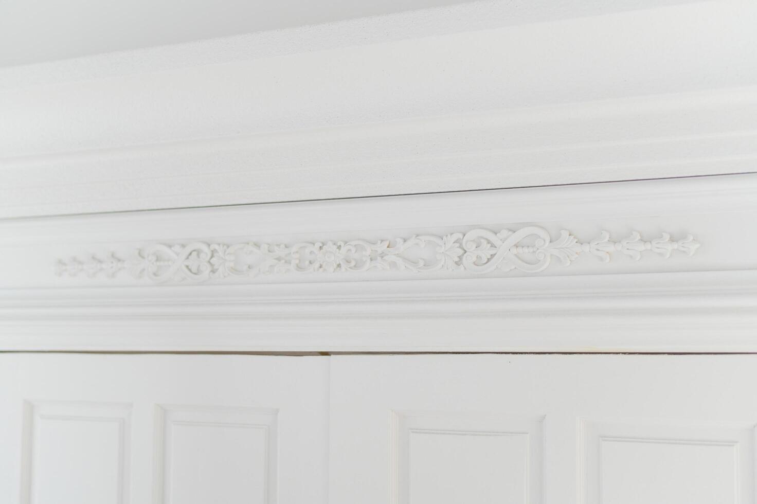 Ornate white crown molding with intricate floral details photo