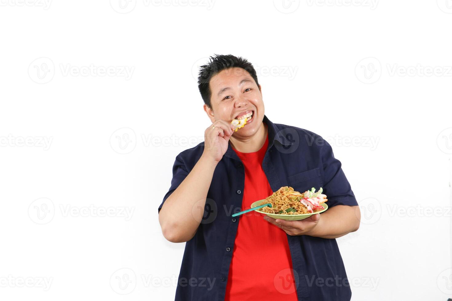 Happy man enjoying delicious a plate of Delicious Indonesian Fried Noodles with crackers photo