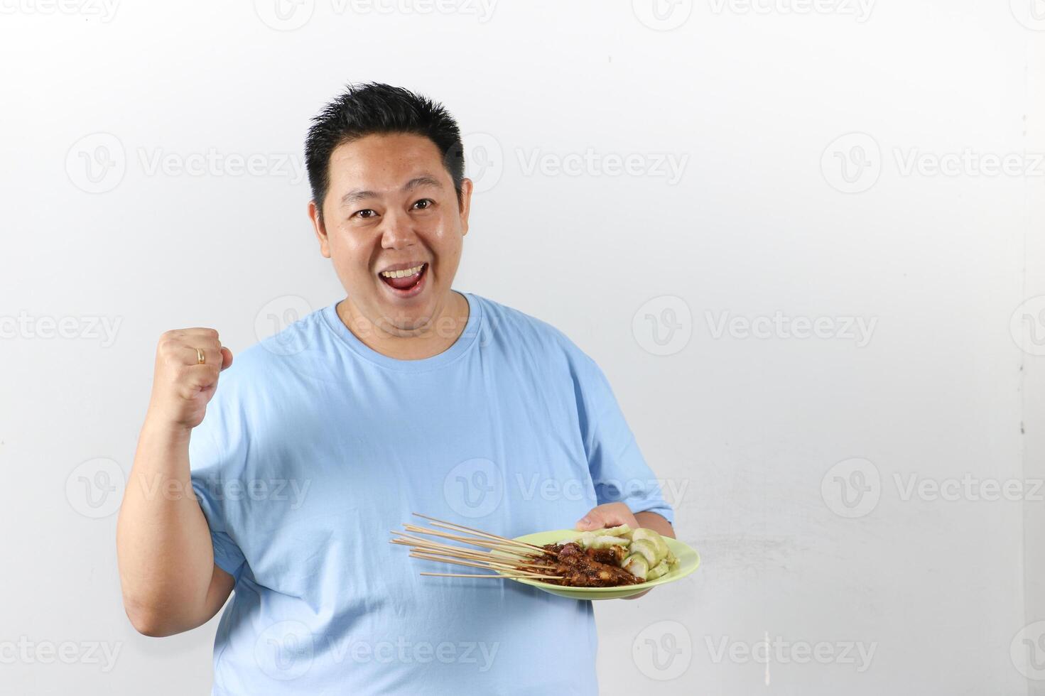 Happy Asian Man Celebrating with Indonesian Chicken Satay Skewers and making YES gesture photo