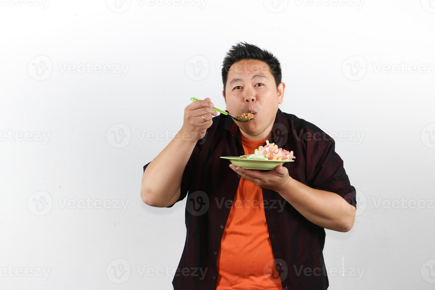 Hungry and Happy Asian man eating Indonesian Fried Rice with a spoon photo
