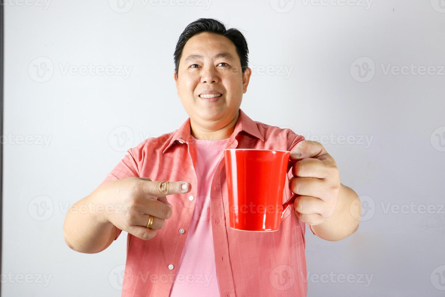 Man Holding a Red Mug and pointing finger into red mug photo
