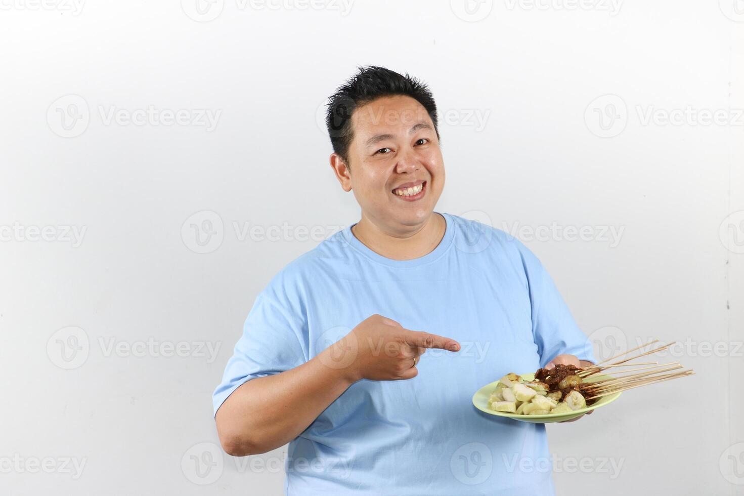 Happy man pointing to delicious Indonesian Chicken satay on a plate photo