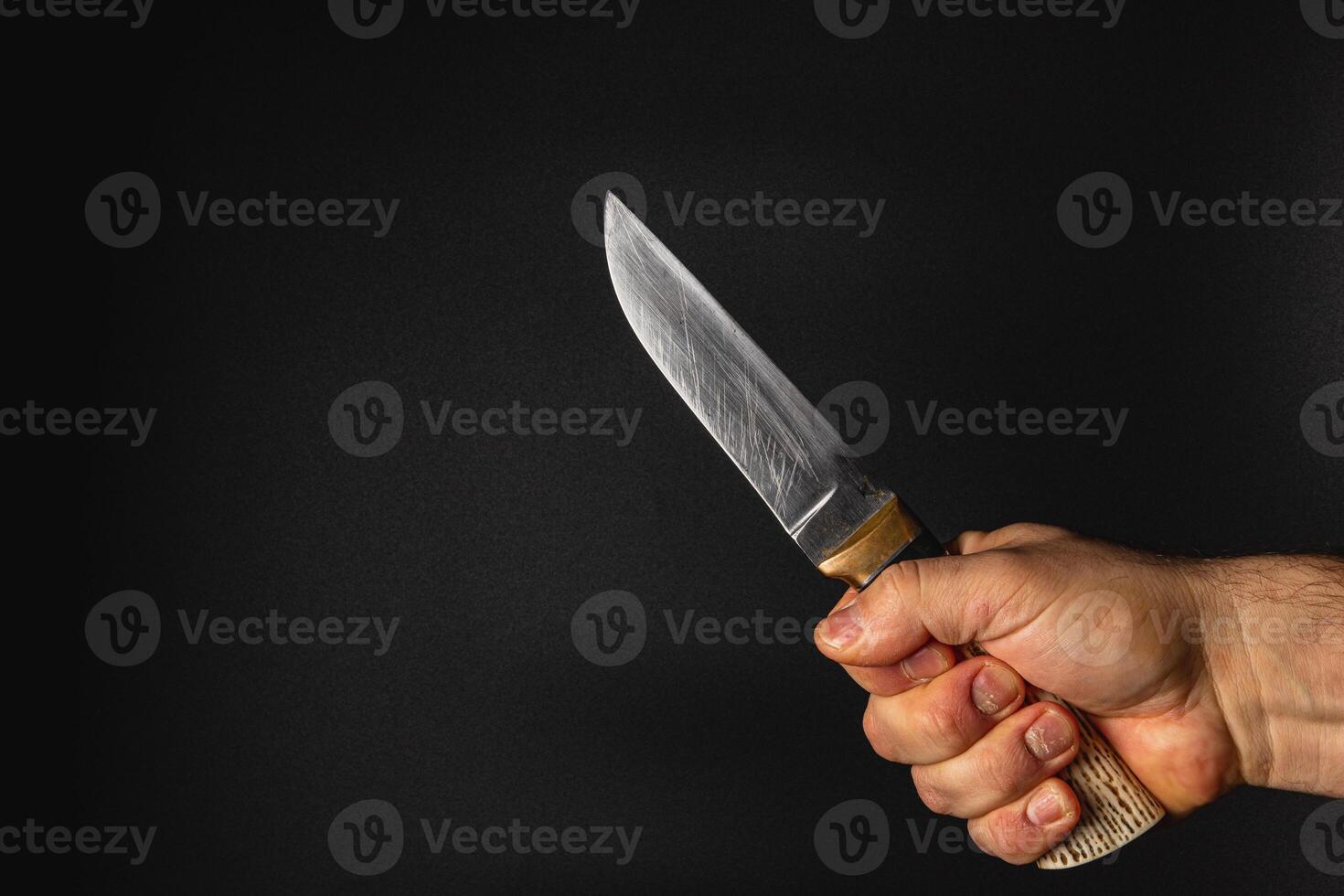 Hand holding a sharp knife against a dark background photo