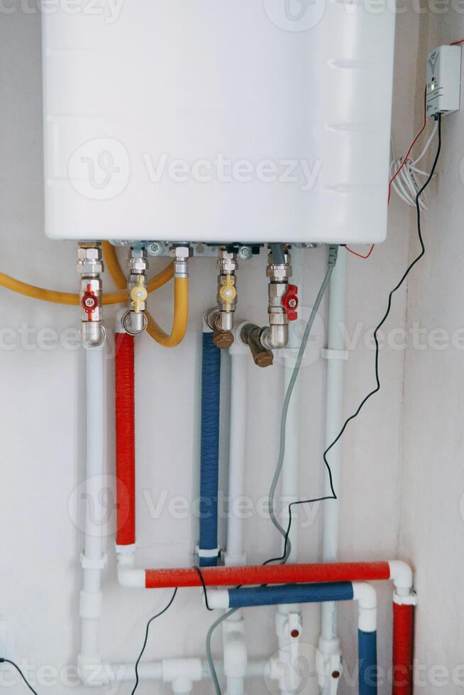 Installation of a gas boiler with colored pipes equipped with valves and connectors for efficient supply of hot and cold water in the residential water supply system photo