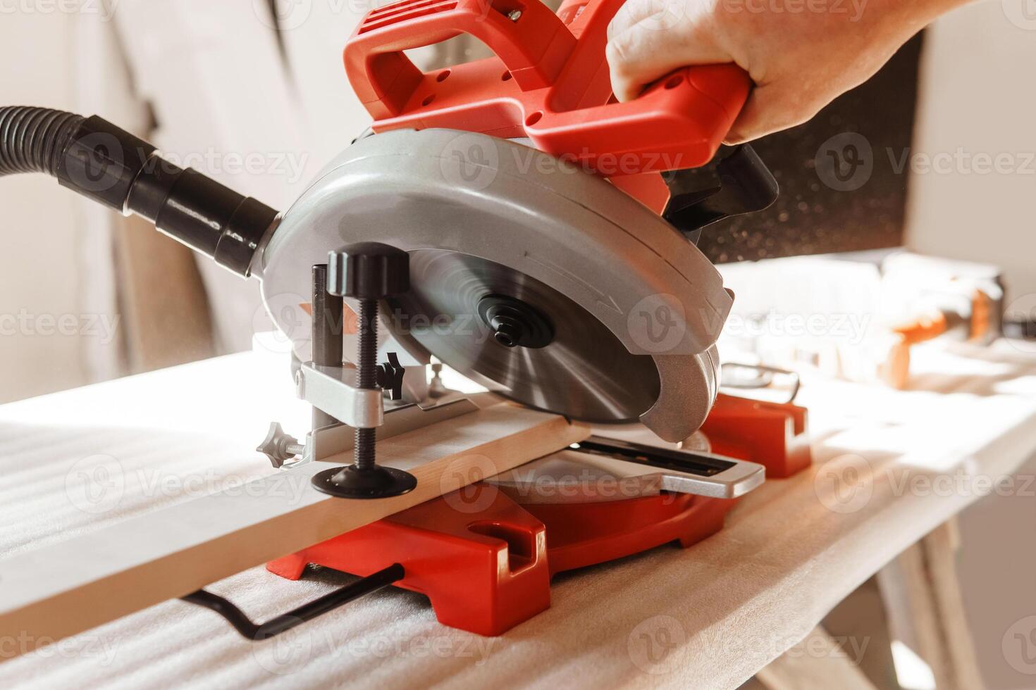 Circular saw in action as carpenter skillfully cuts wooden planks. Hands hold the wood against the saw, showcasing precision and craftsmanship photo