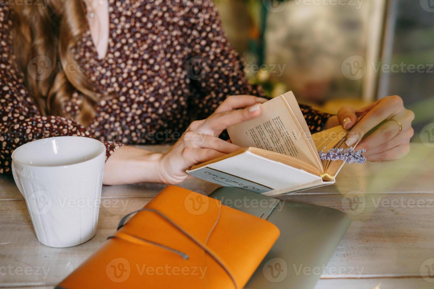 woman sitting at table with a journal, coffee, and flowers around, concentrating while holding a bouquet in a calm and peaceful atmosphere. photo