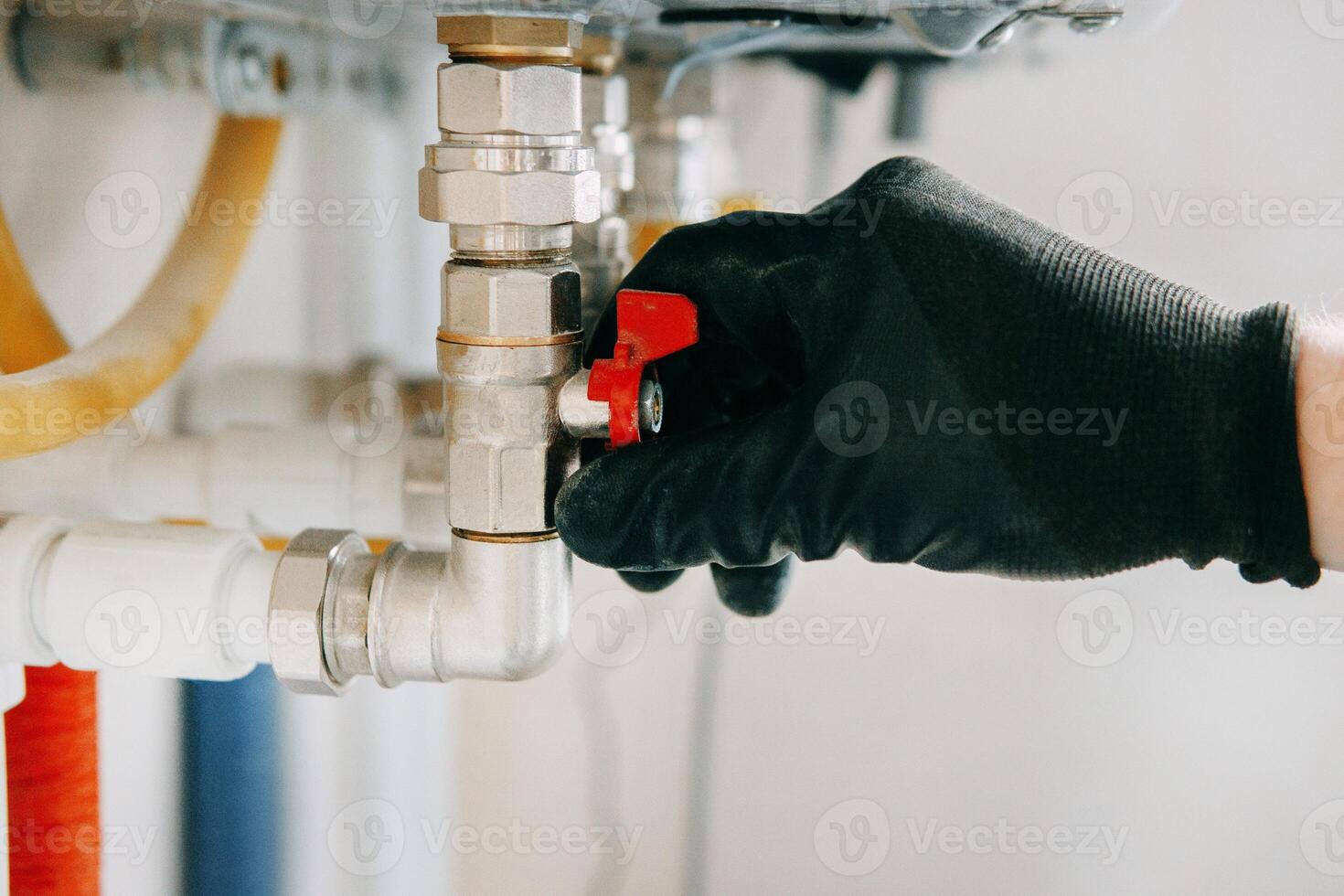 Gloved hand adjusts valve on industrial equipment, showcasing industrial maintenance work. The image highlights the precision and care involved in technical operations. Gas boiler taps. photo
