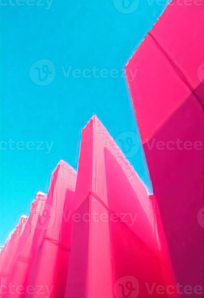Abstract pink geometric structures reach skyward against a vibrant blue sky backdrop. The image captures dynamic lines and vivid colors in a modern, artistic composition. photo
