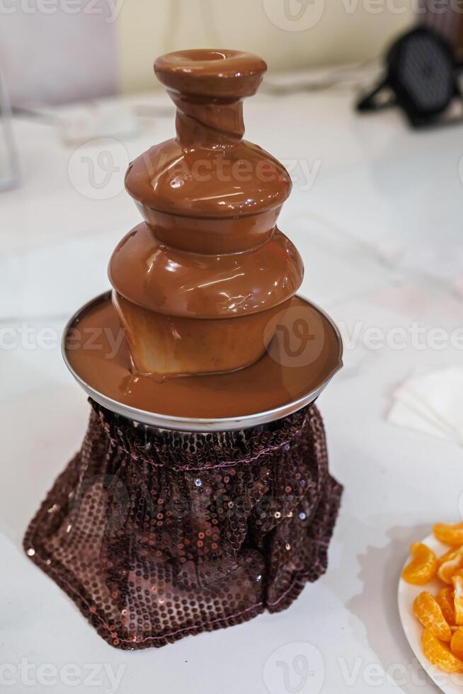 A chocolate fountain with a chocolate cake sitting on top of it photo