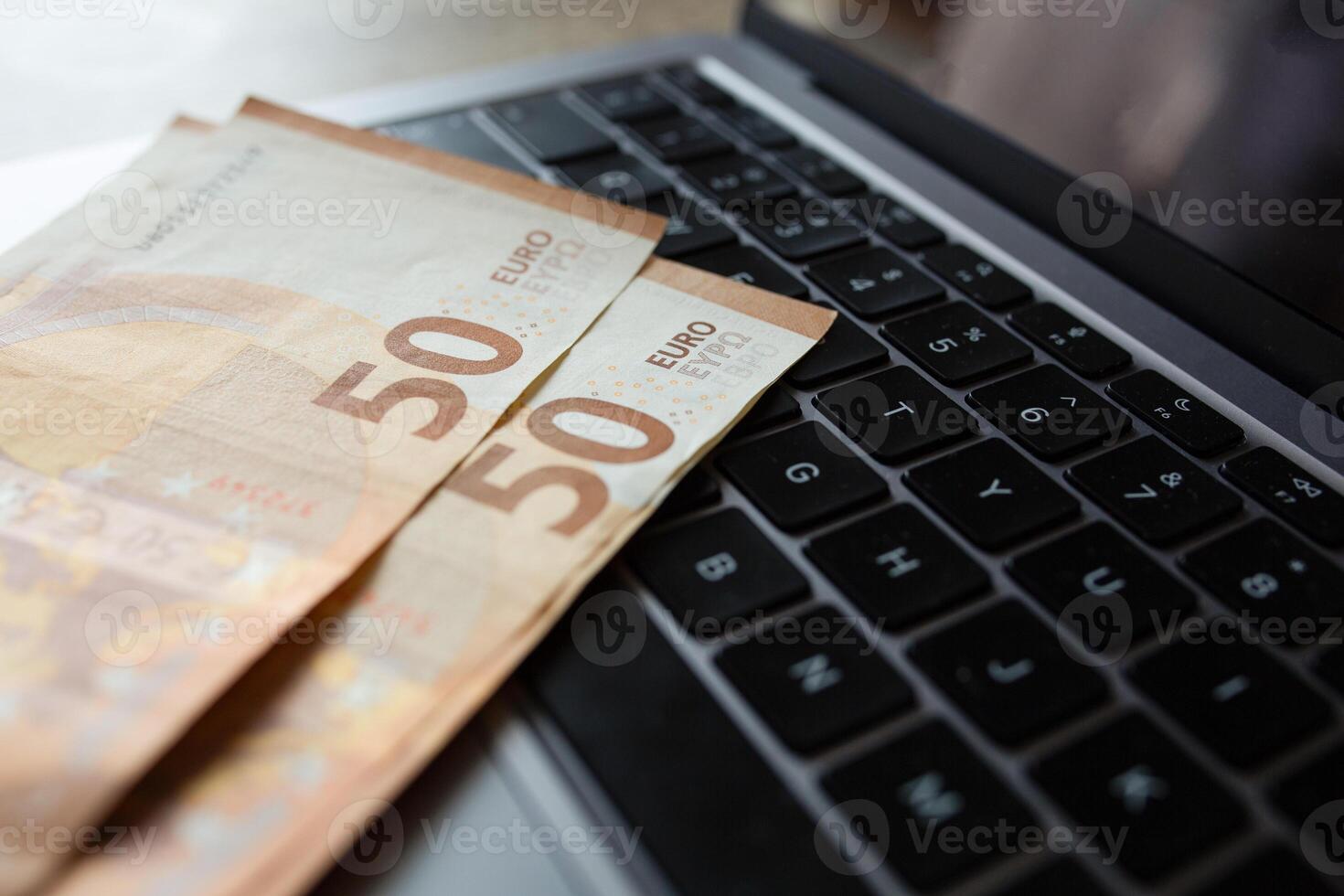 Euro banknotes on laptop keyboard. Concept of cash money, digital payments and financial transactions photo