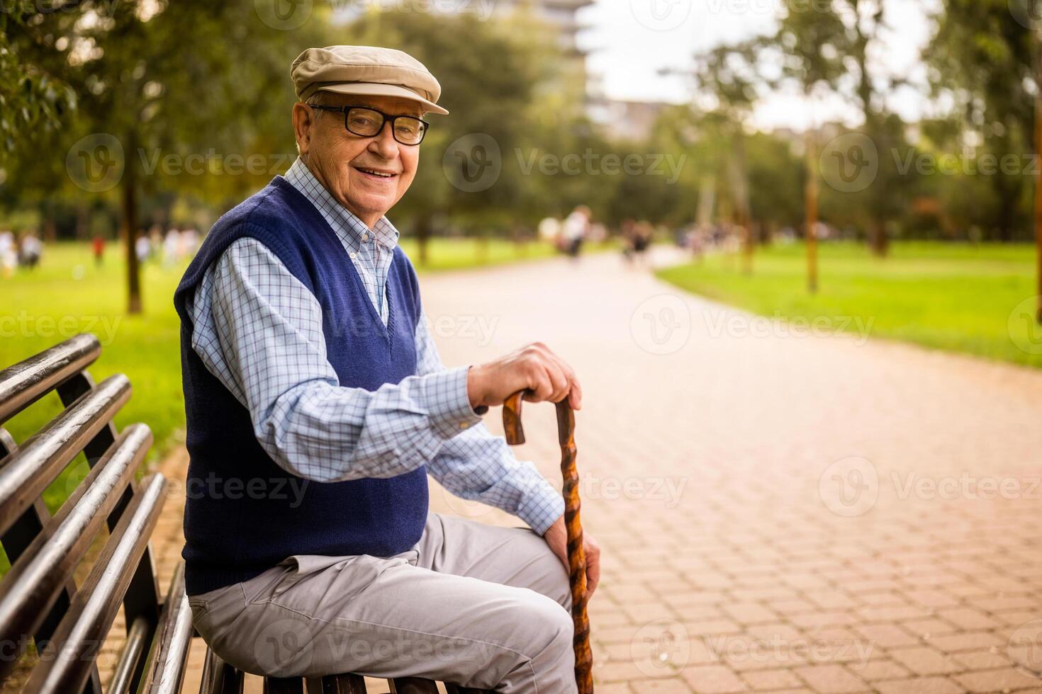 Cheerful senior man in park. He is sitting on bench and enjoying autumn day. photo