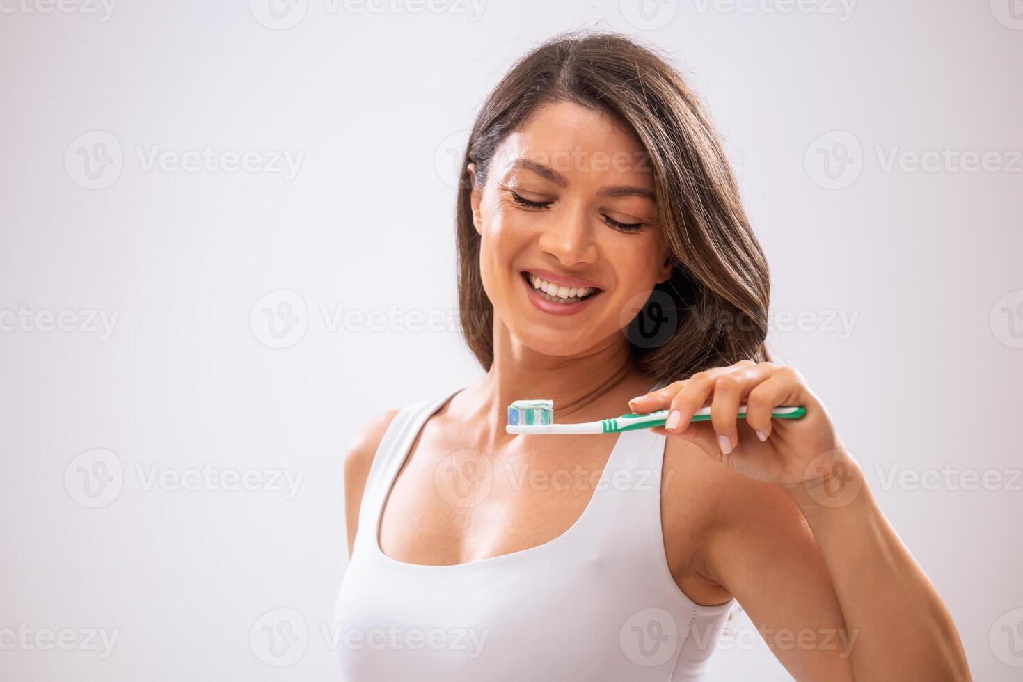 Studio shot of adult woman who is brushing her teeth. photo