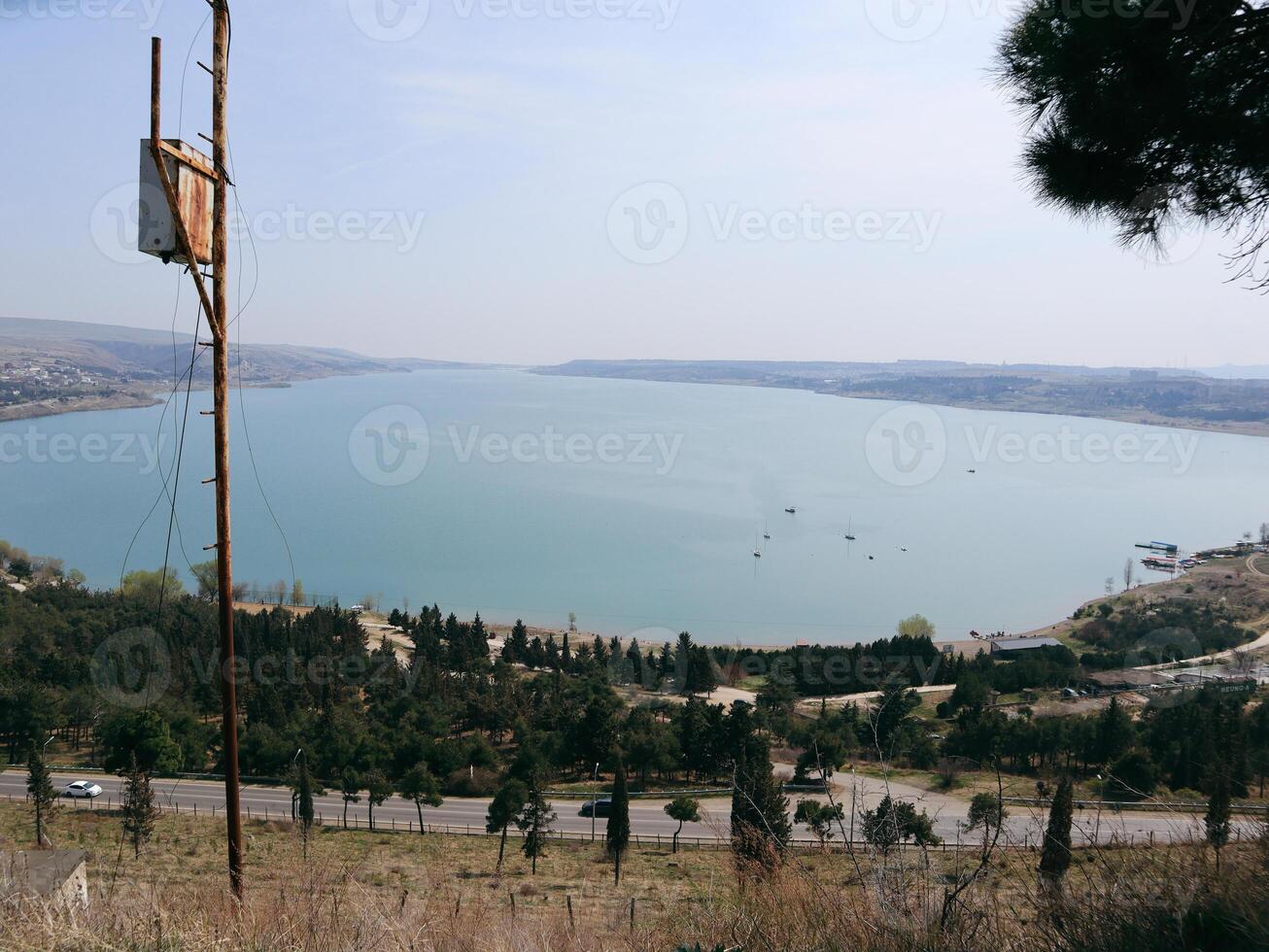 Panoramic View of a Turquoise Lake with Boats and Lush Landscape photo