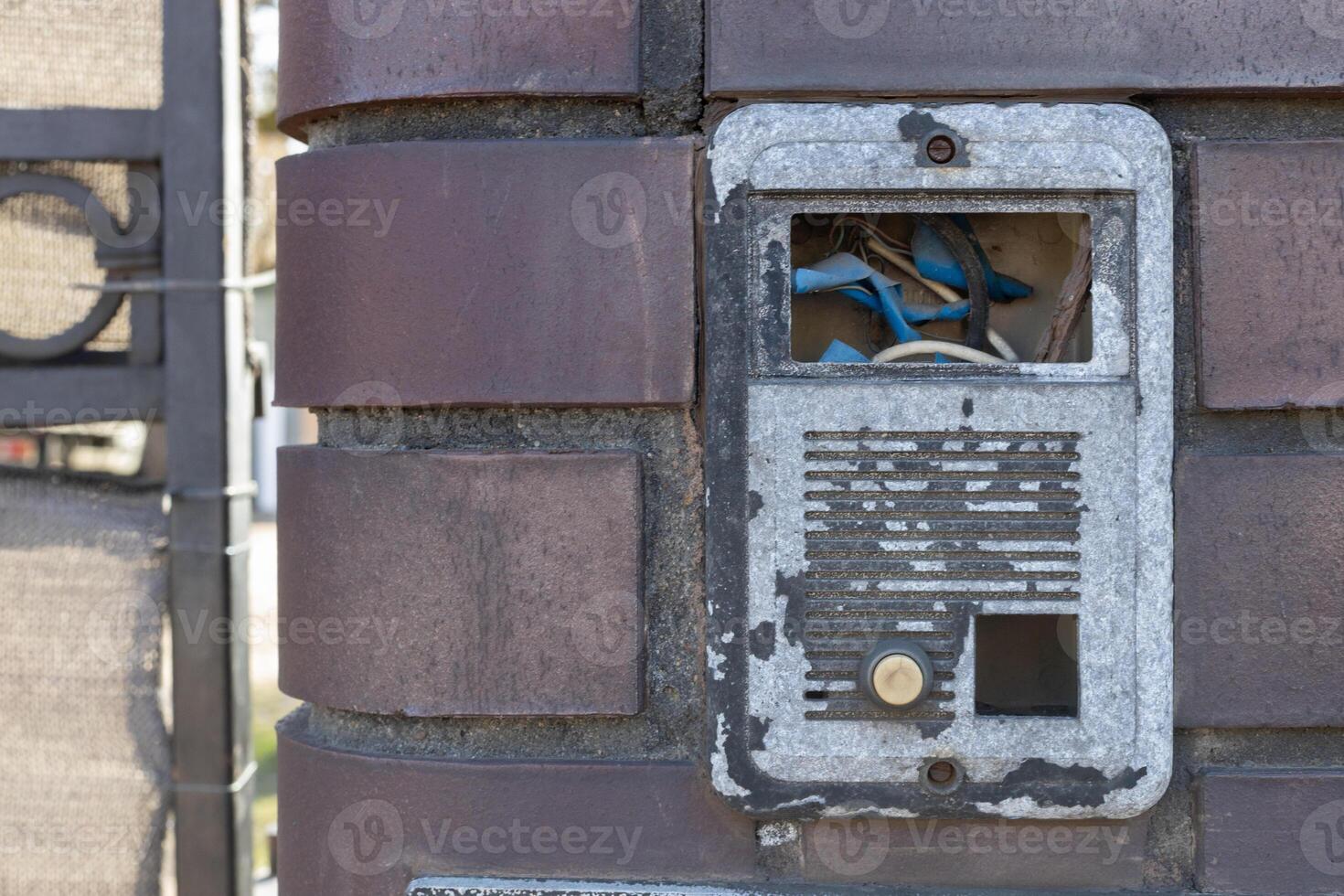 Old Damaged Intercom with Exposed Wires on Brick Wall photo