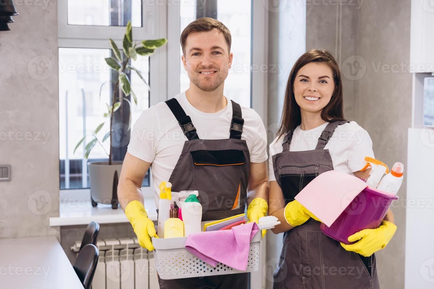 Cleaning company workers holding cleaning products smiling at home photo
