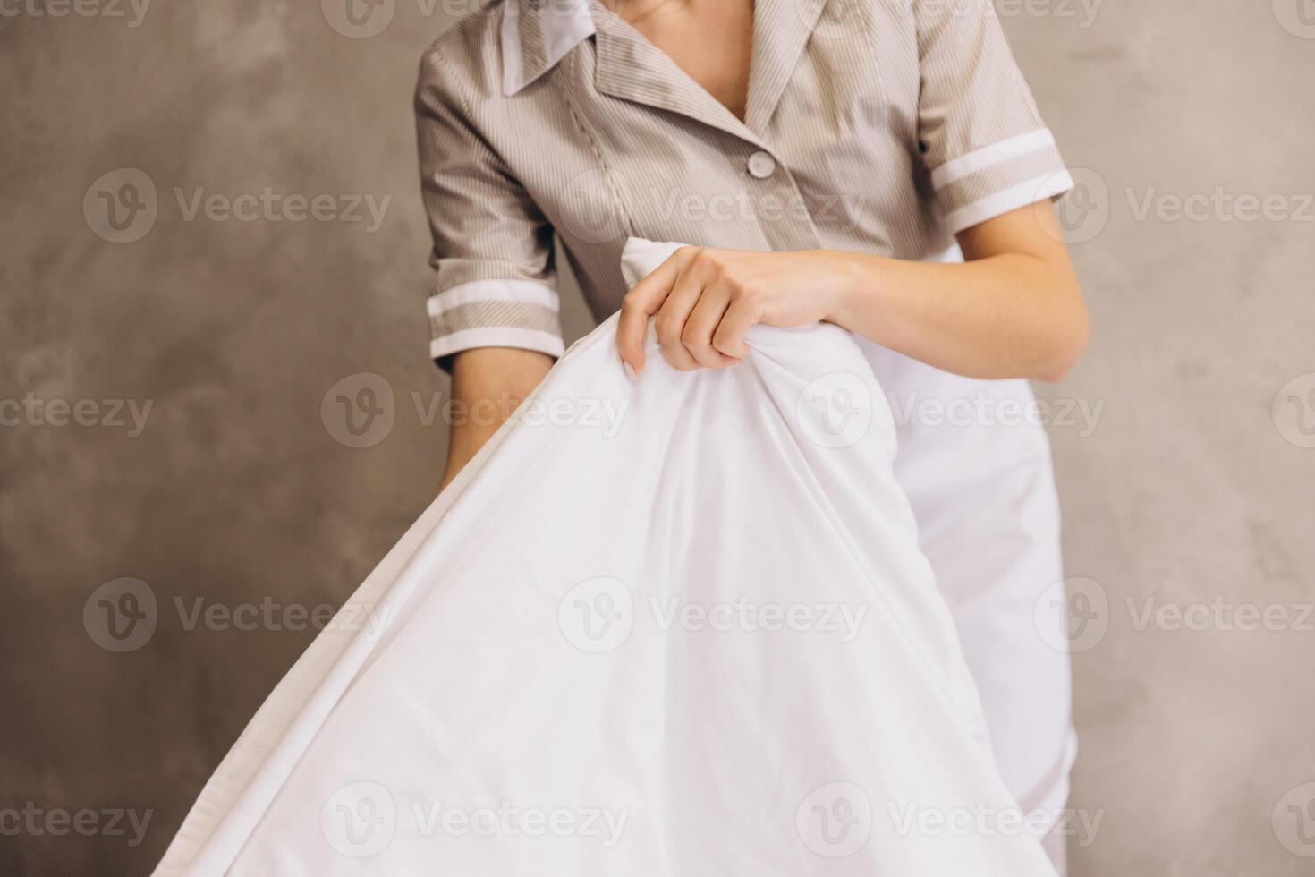 Chambermaid changing bed linen in hotel room photo