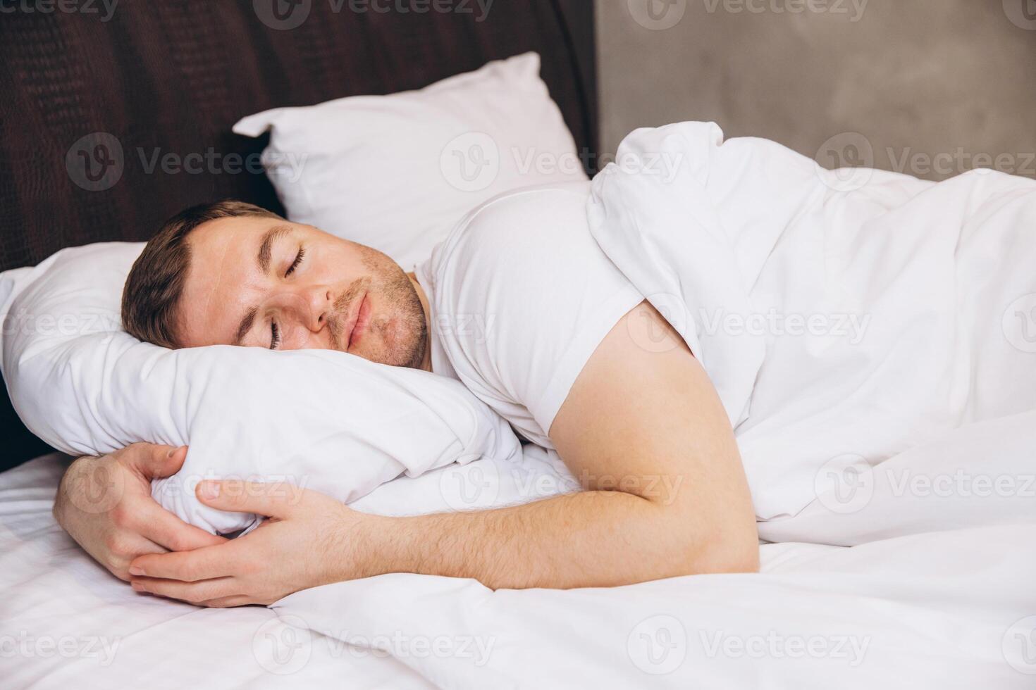 Man Sleeping Peacefully in Comfortable Bed, Hugging Pillow photo