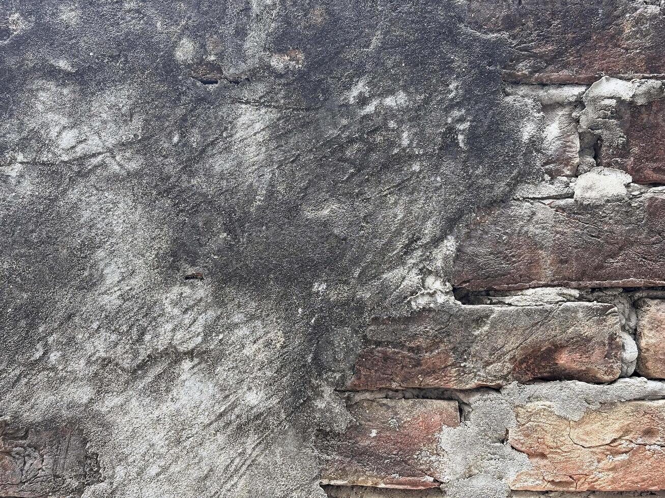 A close up of an Old Aged Damaged Brick wall with bad and crumbled plasterwork photo