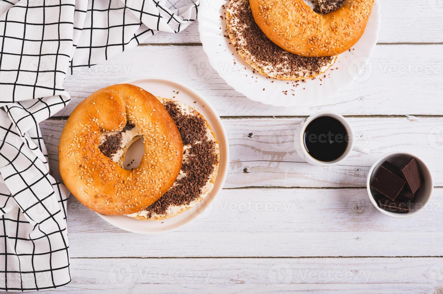 Bagel sandwich with butter and grated chocolate on a plate on a table top view photo