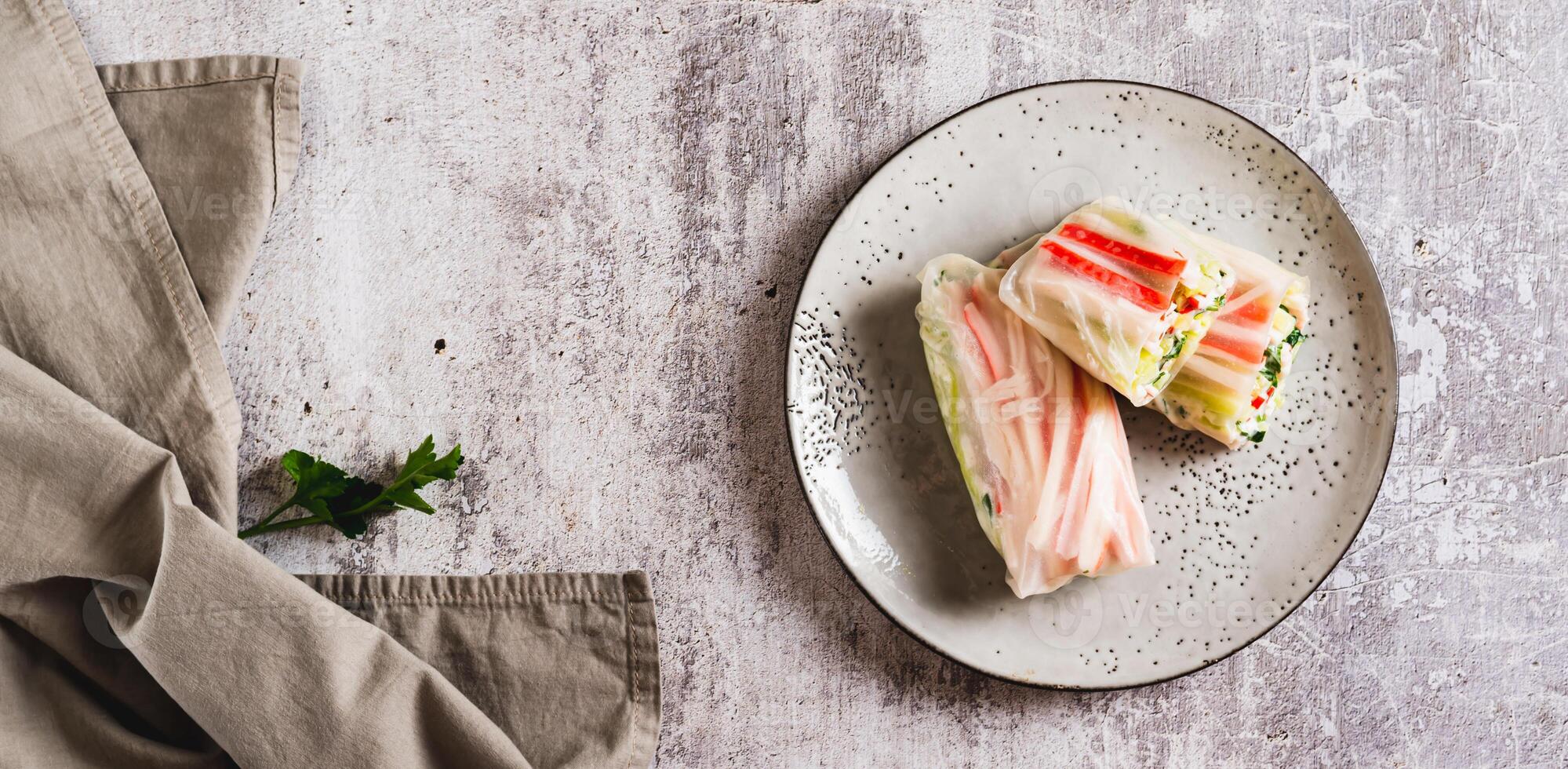 Spring rolls with crab meat, cucumber and herbs on a plate on the table top view web banner photo