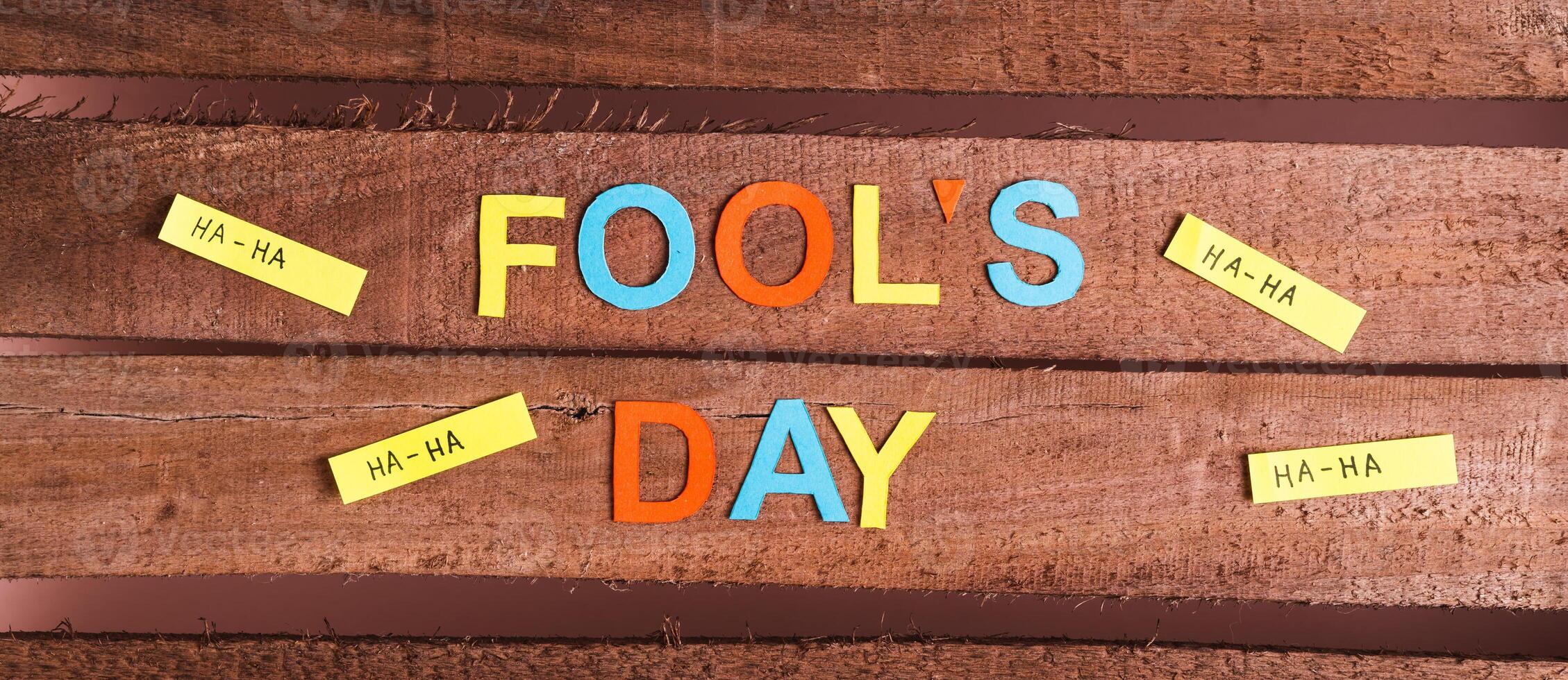 April Fools Day from colored letters, funny notes and paper on wooden top view web banner photo