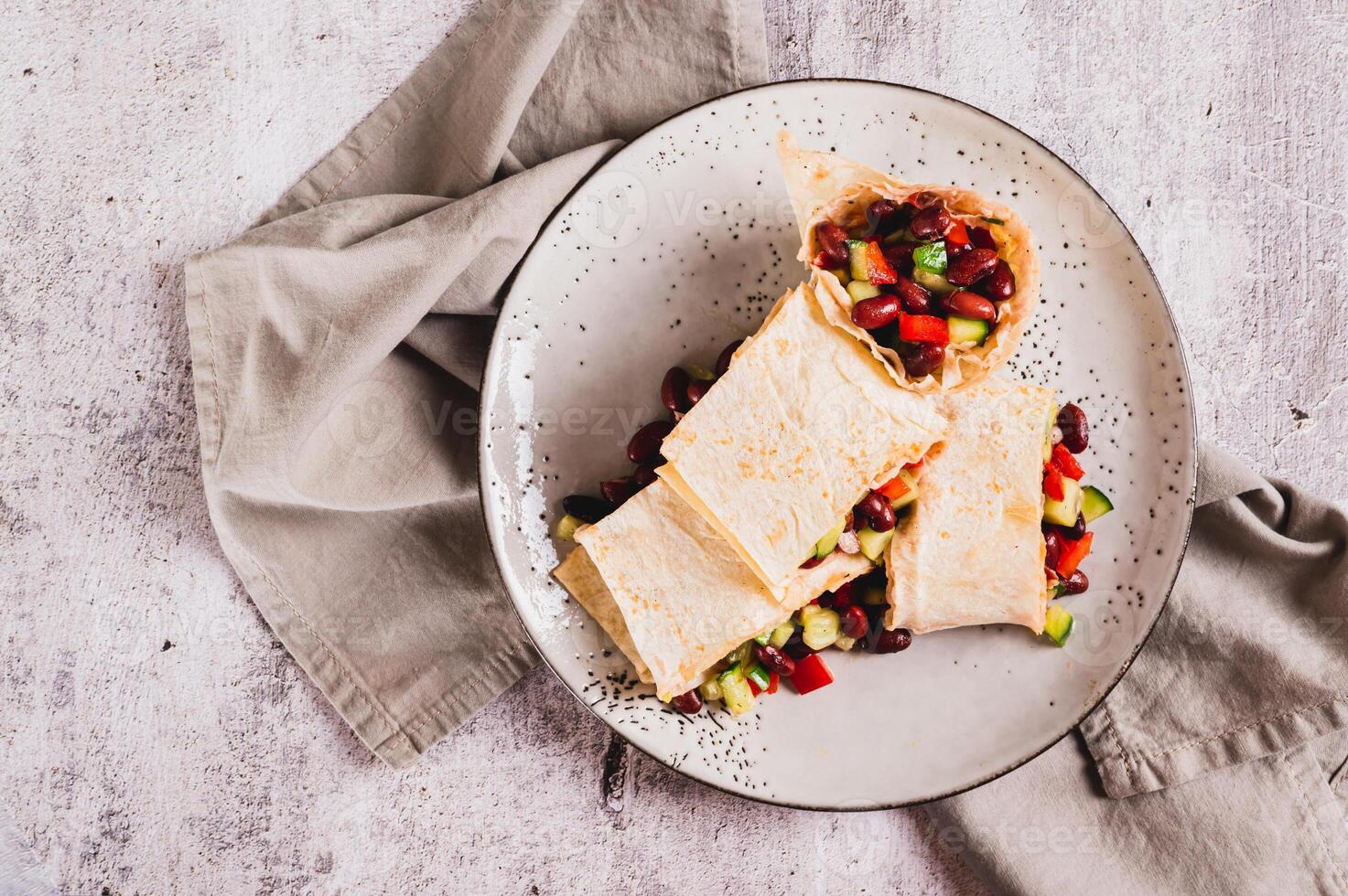 Close up of salad of beans, cucumber and pepper in lavash rolls on a plate on the table top view photo