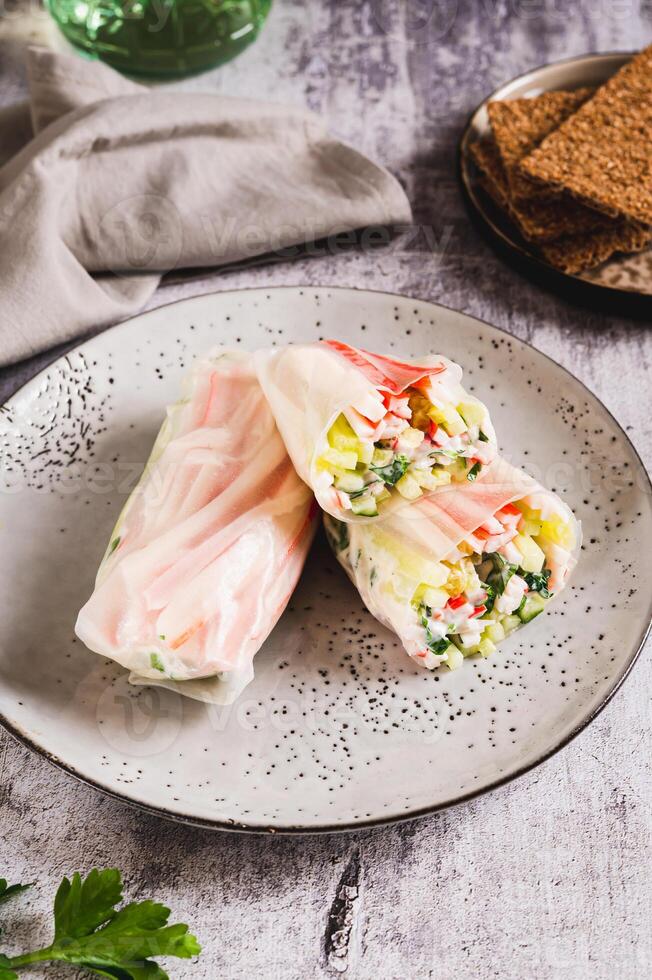 Spring rolls with crab meat, cucumber and herbs on a plate on the table vertical view photo