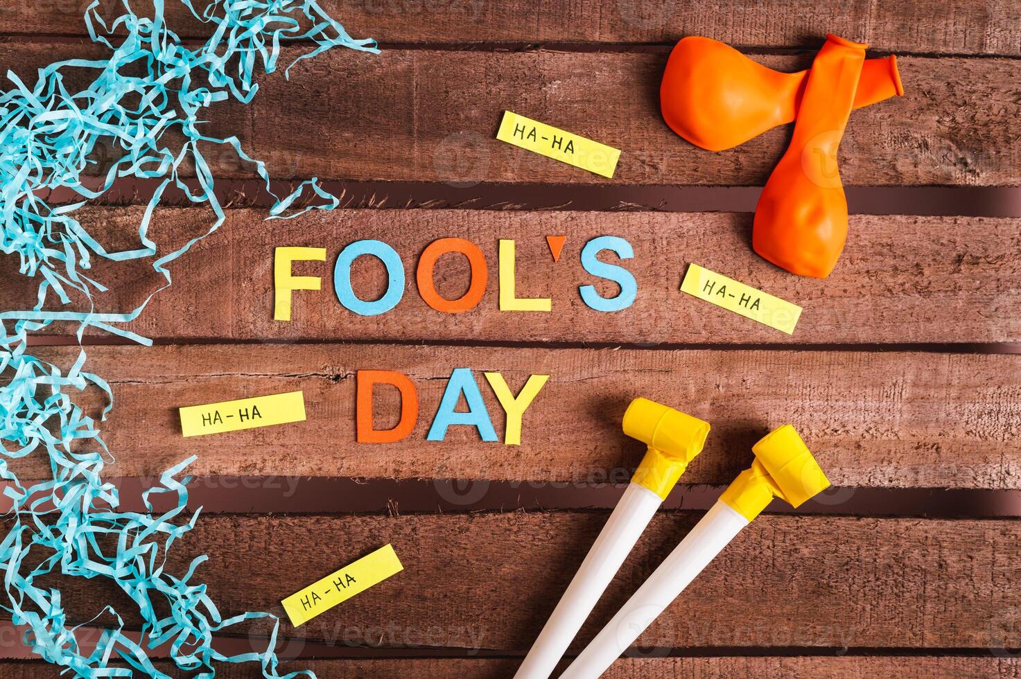 April Fools' Day from colored letters, funny notes, whistles and balloons on a wooden background photo