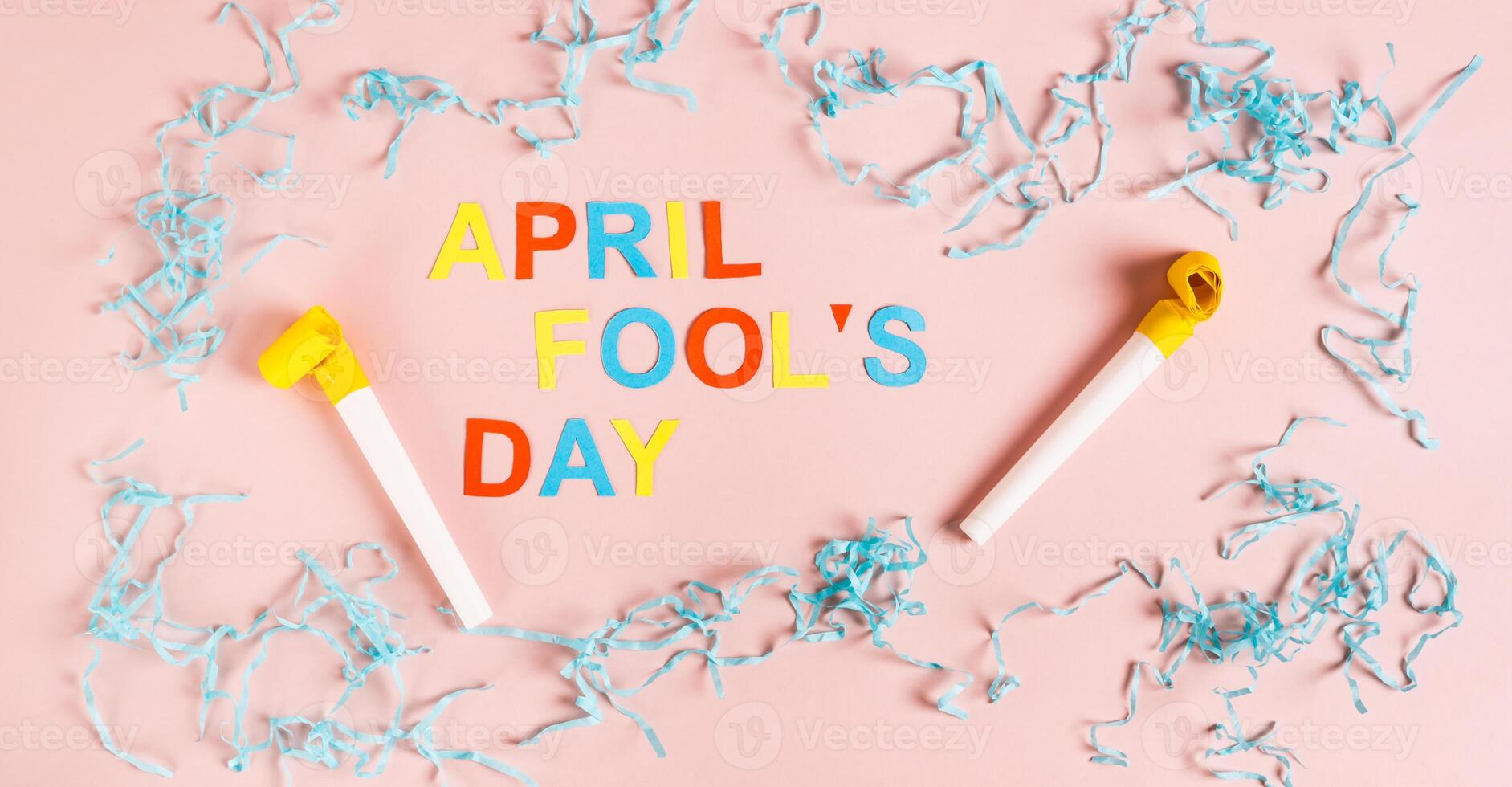 April Fools' Day from colored letters, whistles, balloons and paper on pink top view web banner photo