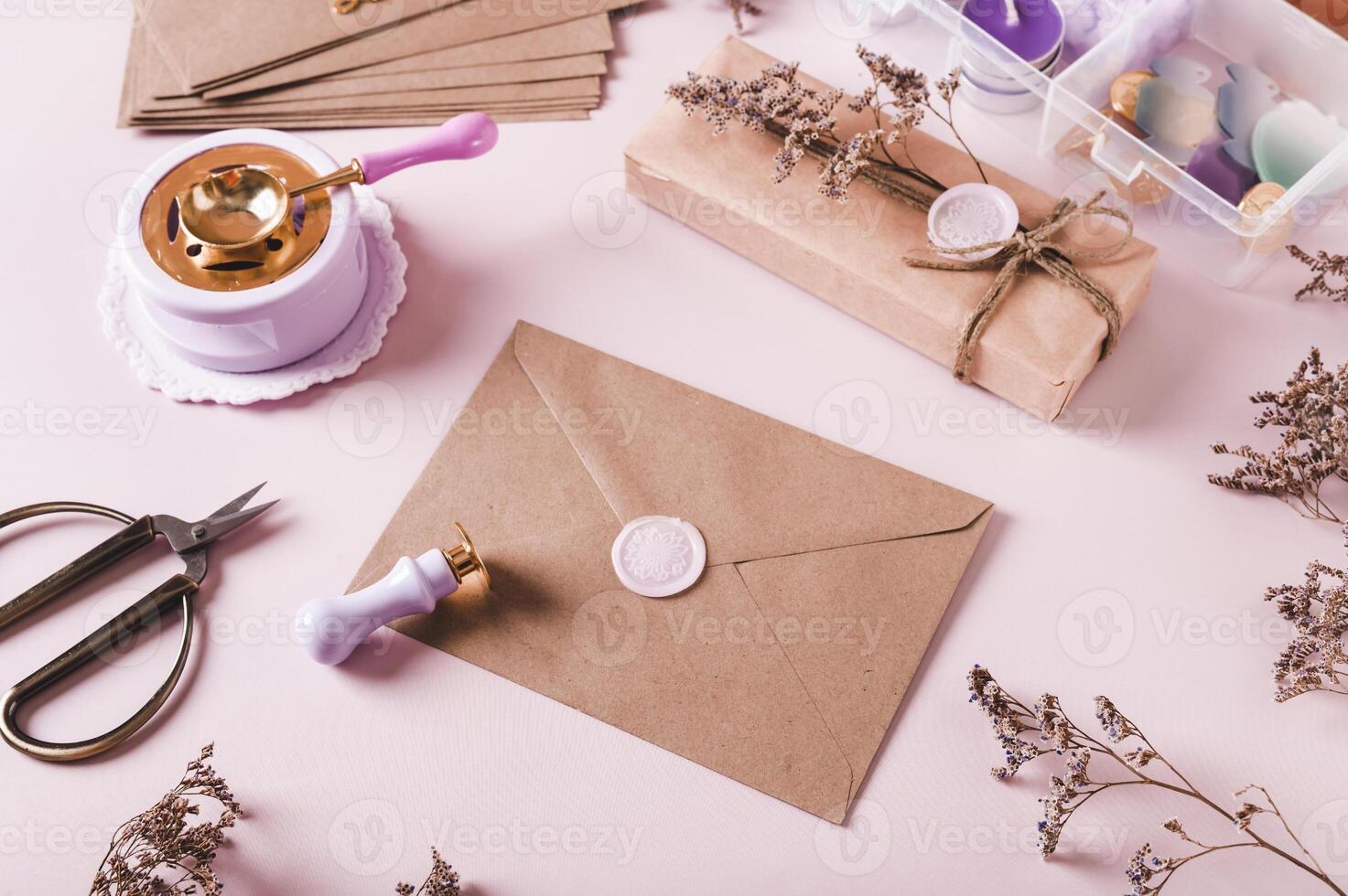 Craft envelope with wax seal and crafting items on pink photo