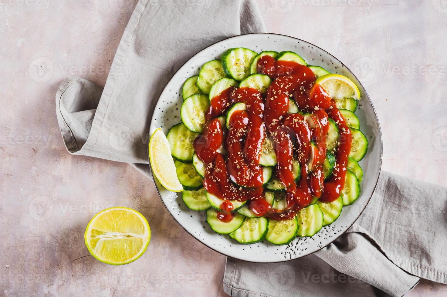 Close up of mexican spicy cucumbers with chili sauce and lime on a plate on the table top view photo