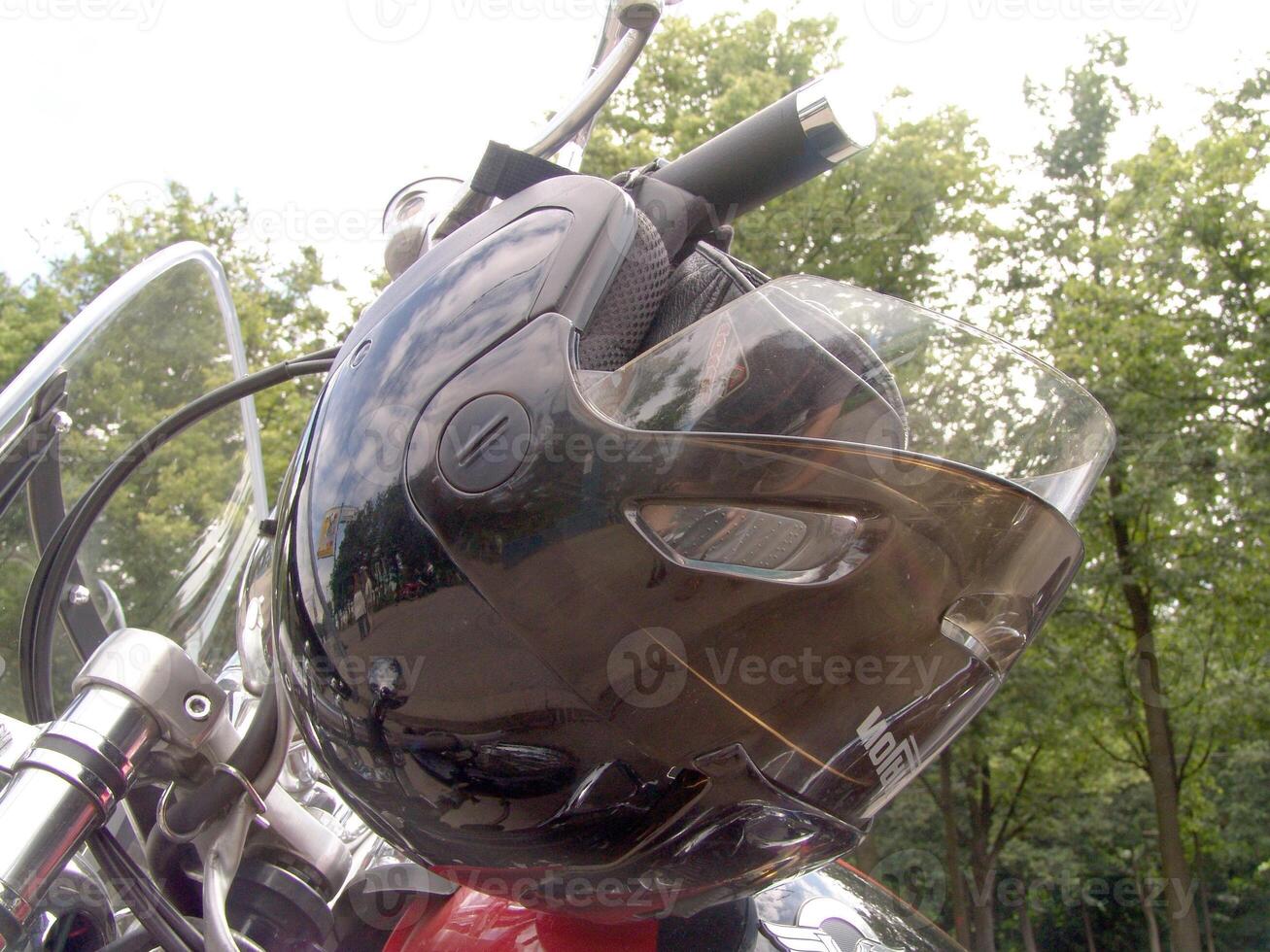 Motorcycle Helmet Hanging on Handlebar Outdoors photo