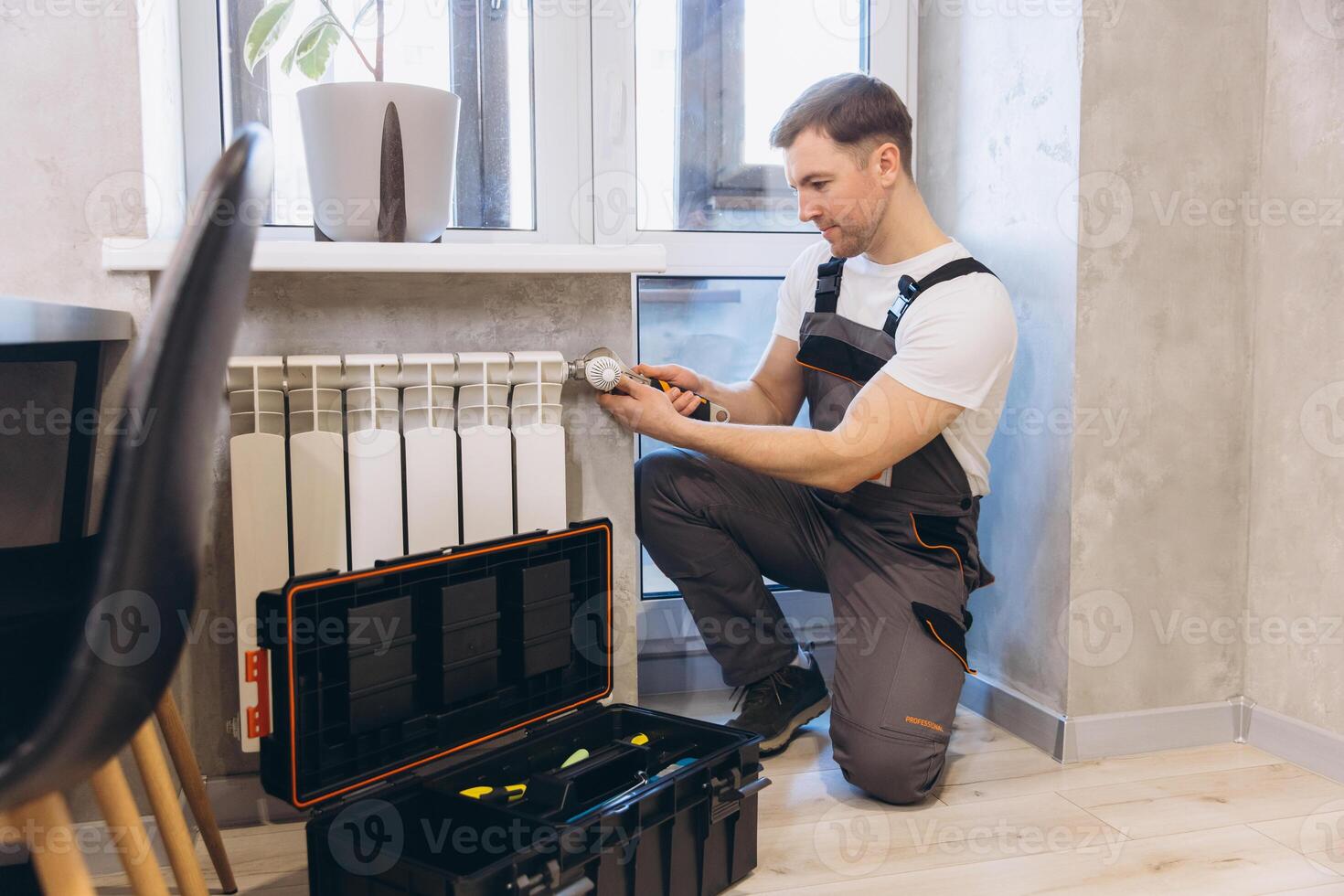 Plumber Installing Thermostat Valve on Radiator in Apartment photo