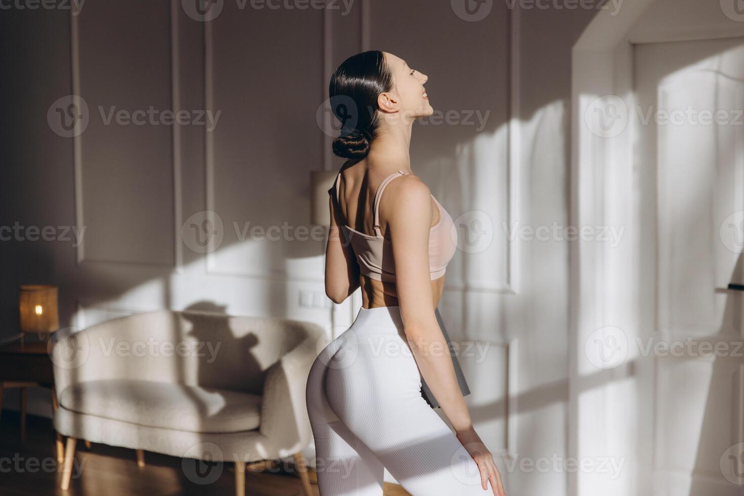 Young woman practicing yoga at home in sportswear enjoying sunlight photo