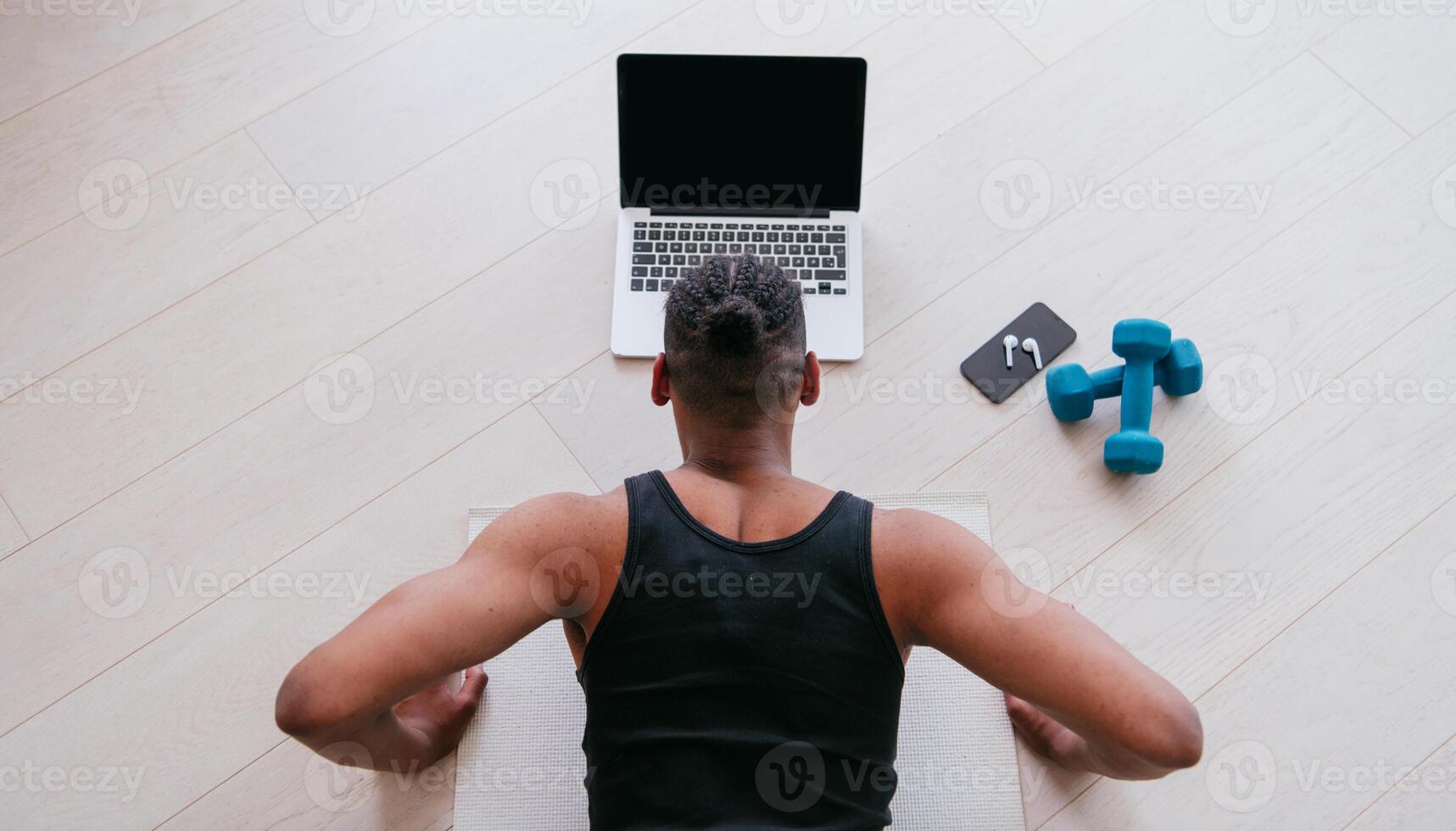 Training At Home. Sporty man doing the training while watching an online tutorial on a laptop, exercising in the living room, free space. photo