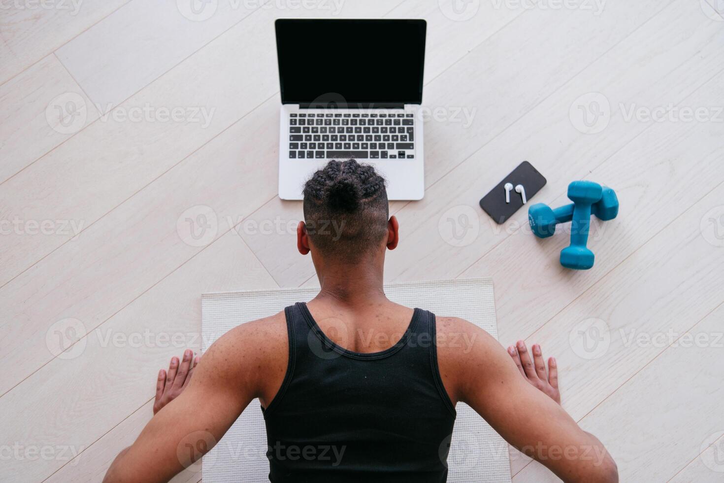 Training At Home. Sporty man doing the training while watching an online tutorial on a laptop, exercising in the living room, free space. photo