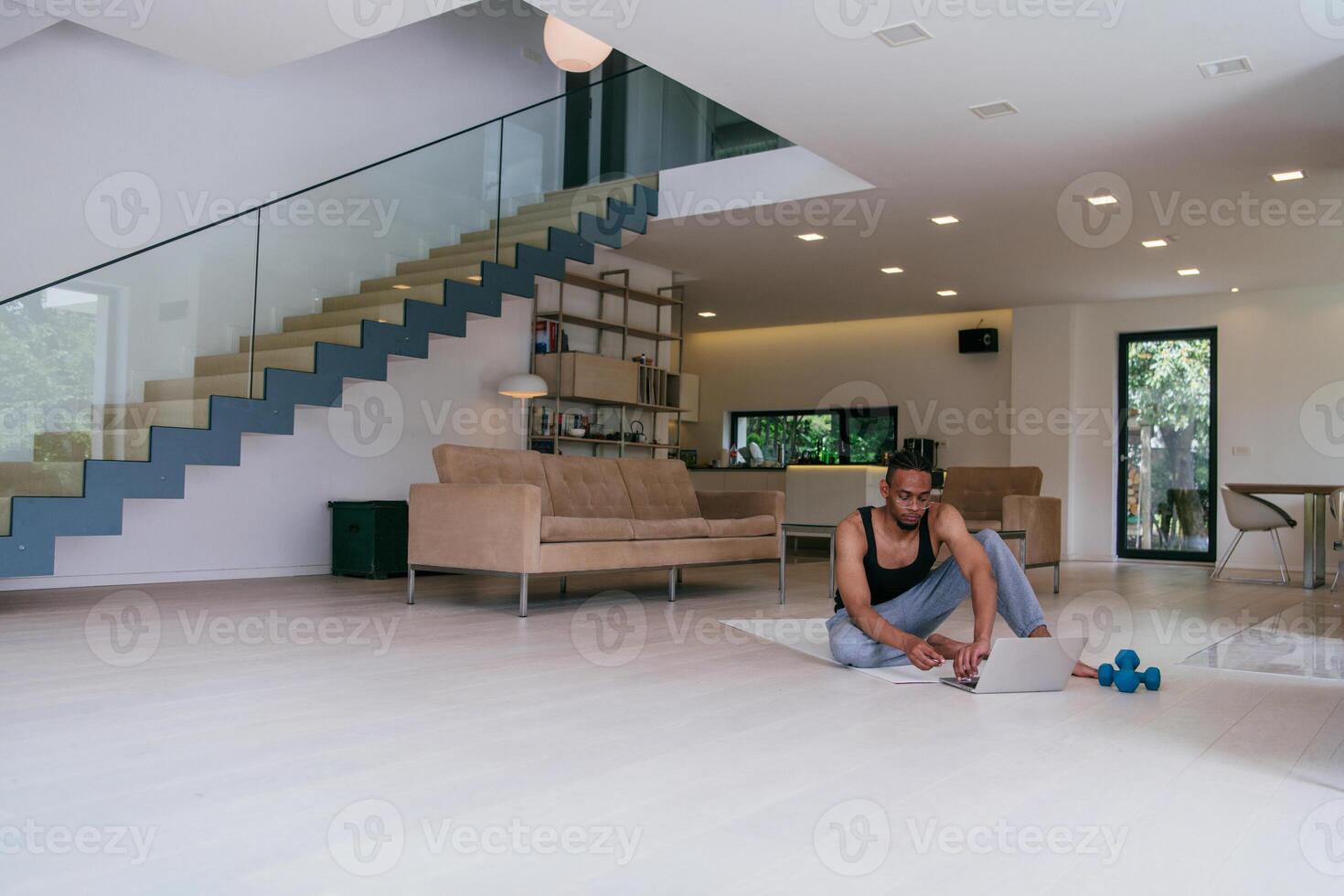 Training At Home. Sporty African American man doing the training while watching an online tutorial on a laptop, exercising in the living room, free space photo