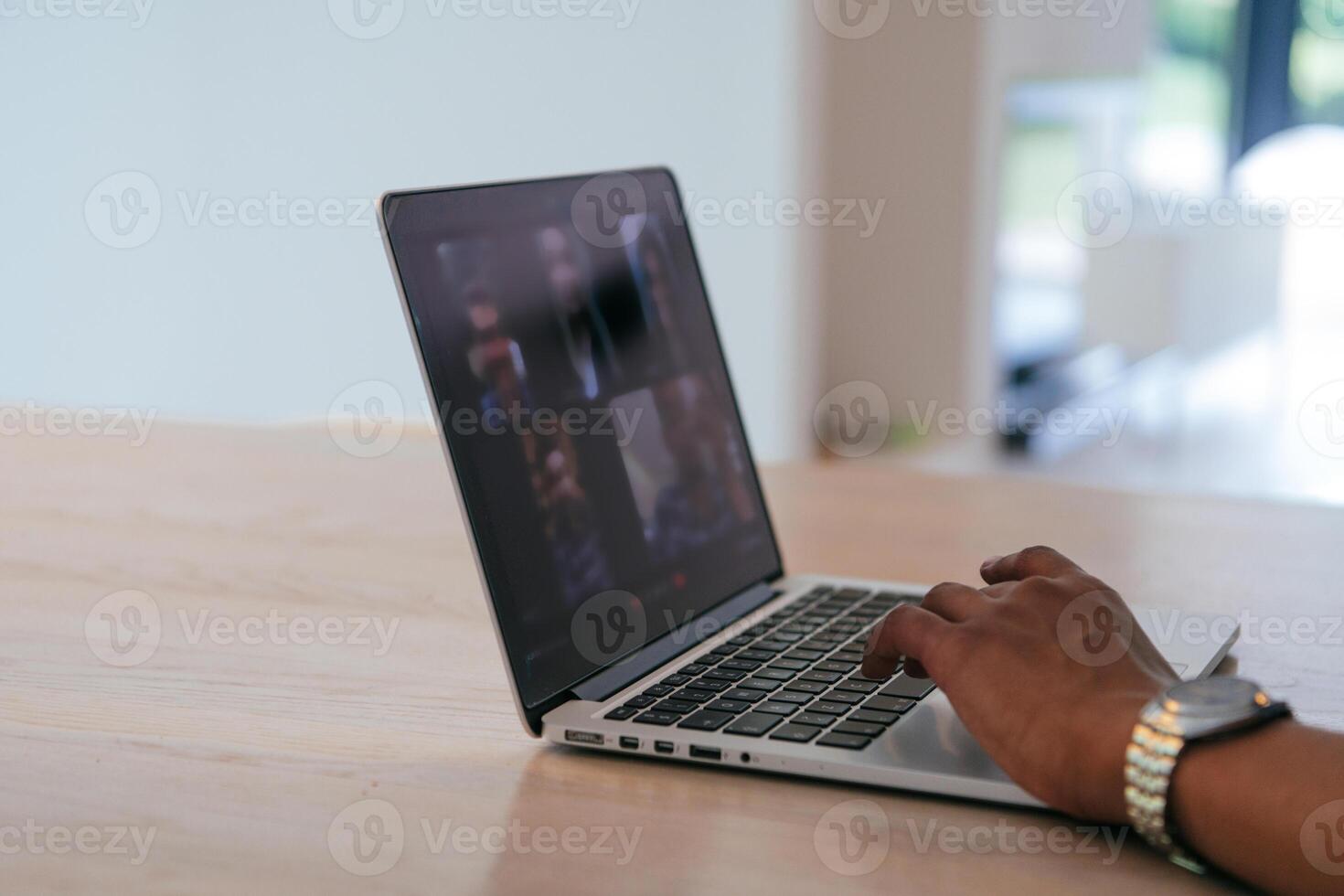 Photo of a laptop with modern headphones on a wooden table in a house with a modern interior.