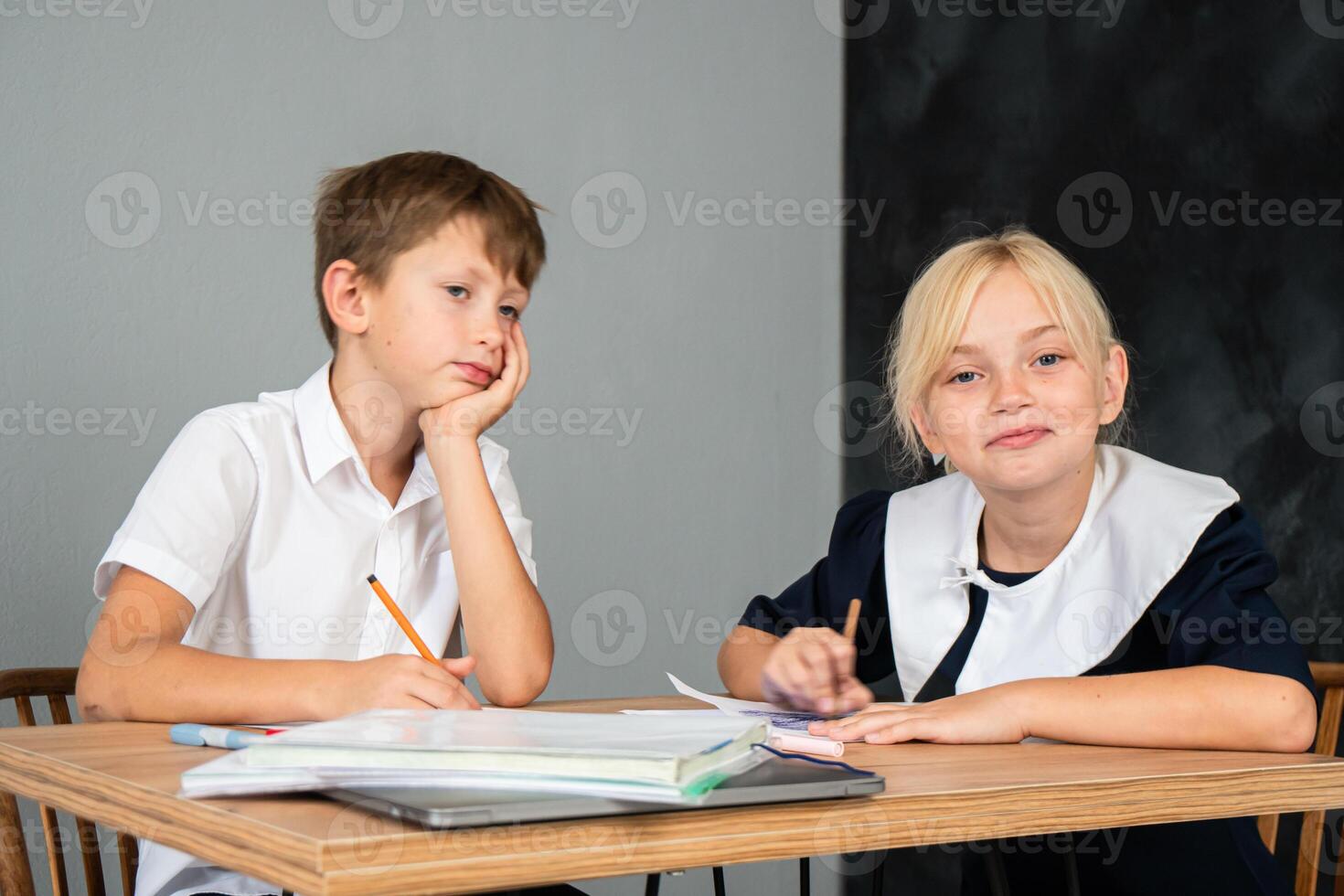 Children School Classroom Studying - Two children in school uniforms are studying in a classroom. photo