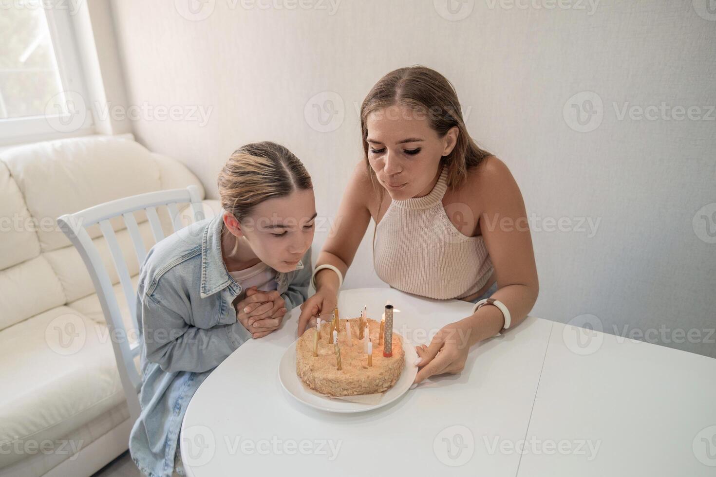 Birthday Cake Women Home Celebration. Two women blow out candles on a birthday cake during an intimate home celebration. photo