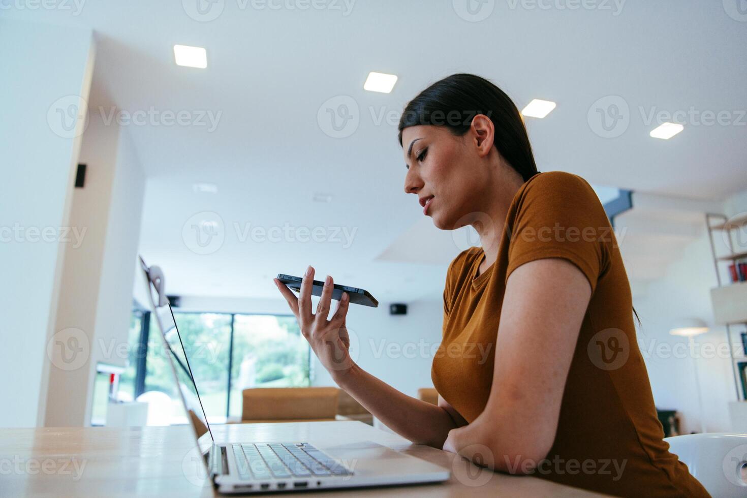 A woman sitting in the living room using a laptop and a smartphone look at camtalk by call with business friends and relatives, head shot. Job interview answering questions. photo