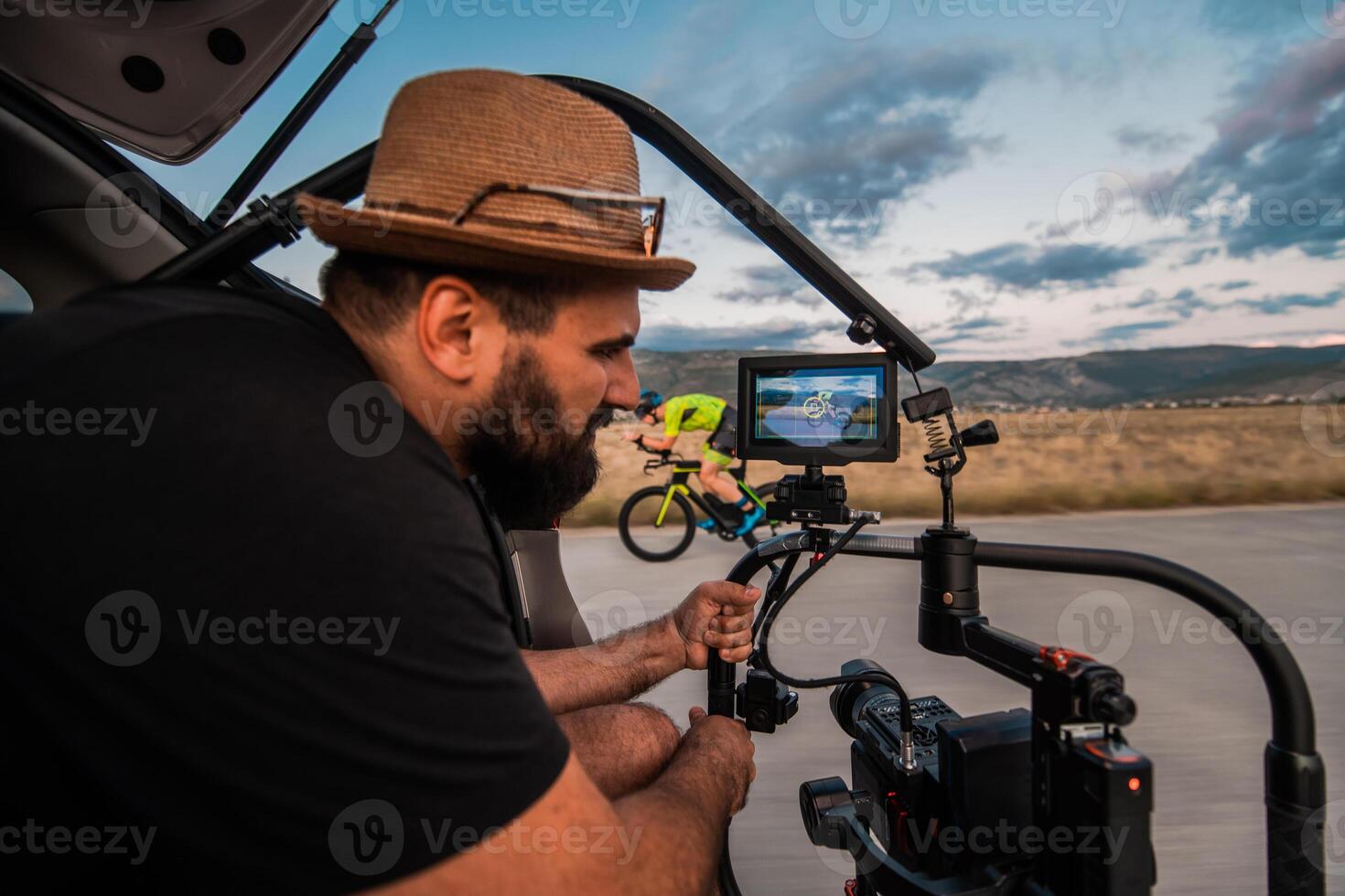 A videographer recording a triathlete riding his bike preparing for an upcoming marathon.Athlete's physical endurance and the dedication required to succeed in the sport. photo