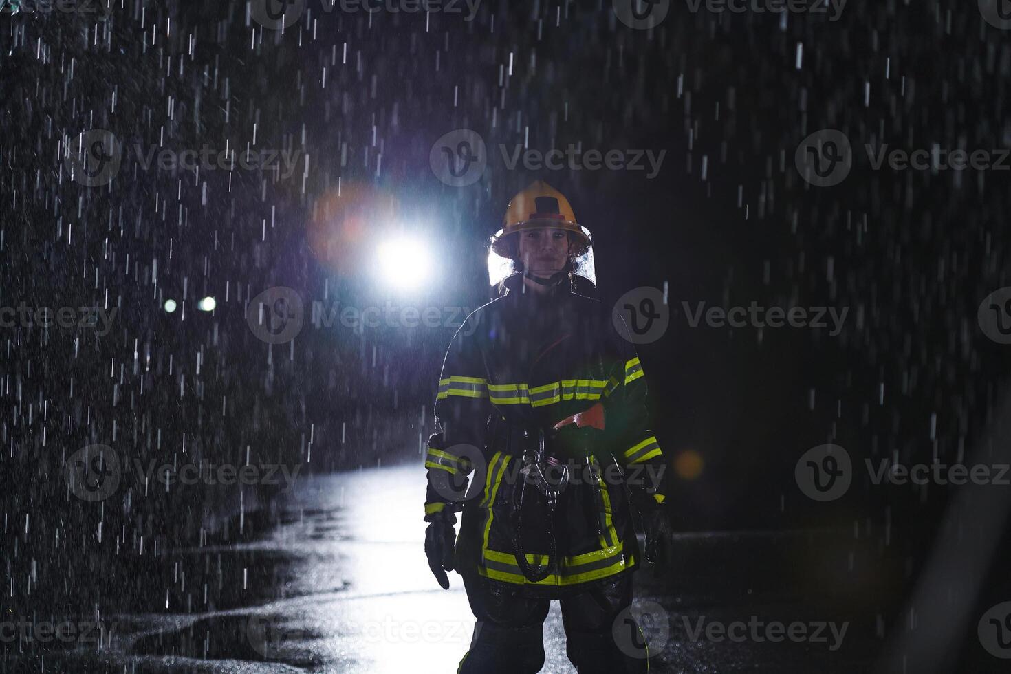 A determined female firefighter in a professional uniform striding through the dangerous, rainy night on a daring rescue mission, showcasing her unwavering bravery and commitment to saving lives. photo