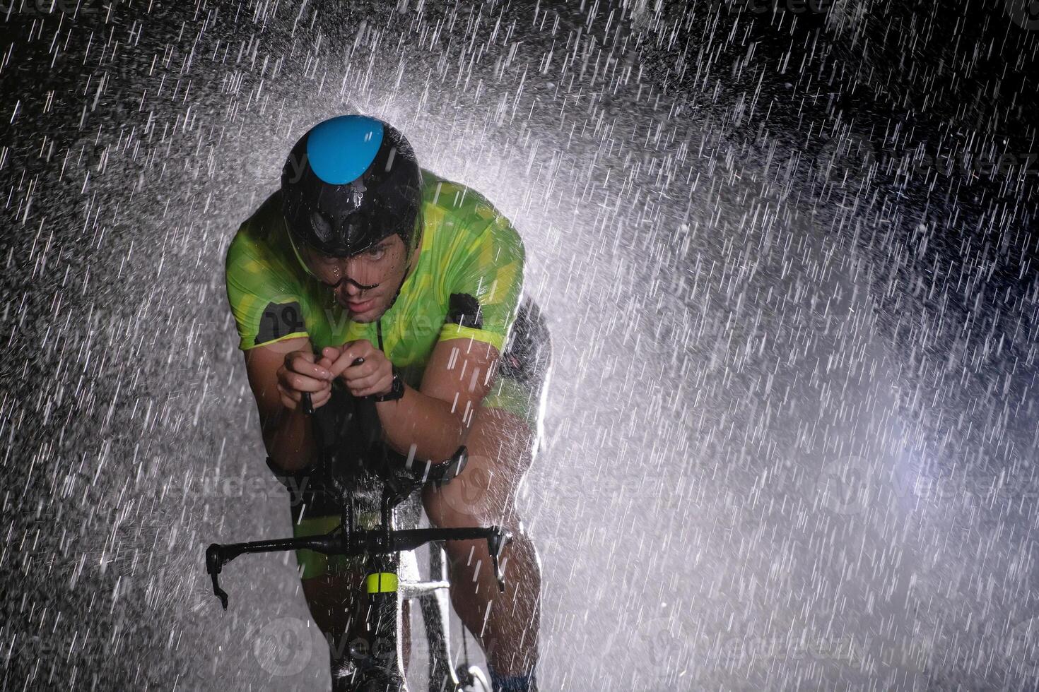 A triathlete braving the rain as he cycles through the night, preparing himself for the upcoming marathon photo