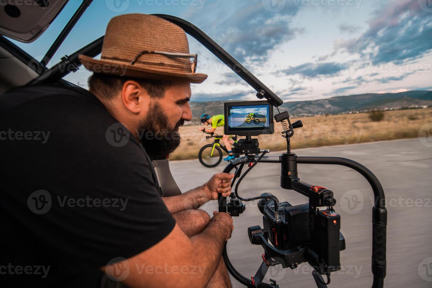 A videographer recording a triathlete riding his bike preparing for an upcoming marathon.Athlete's physical endurance and the dedication required to succeed in the sport. photo