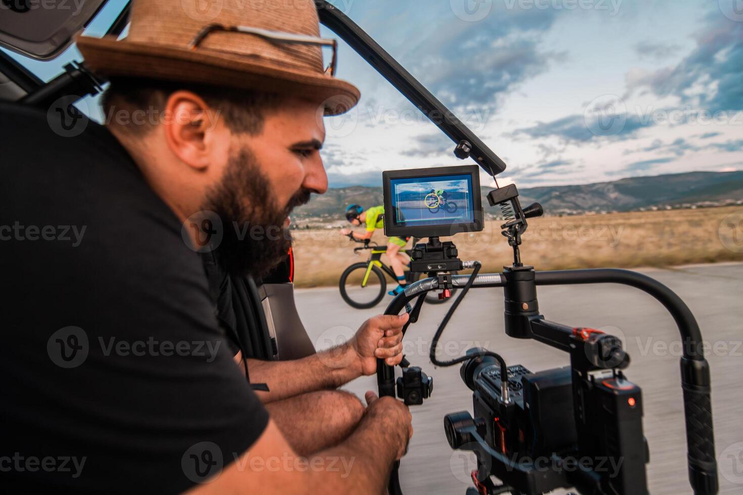 A videographer recording a triathlete riding his bike preparing for an upcoming marathon.Athlete's physical endurance and the dedication required to succeed in the sport. photo