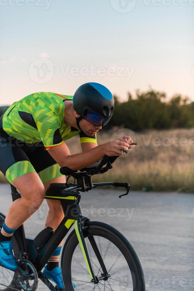 Triathlete riding his bicycle during sunset, preparing for a marathon. The warm colors of the sky provide a beautiful backdrop for his determined and focused effort. photo